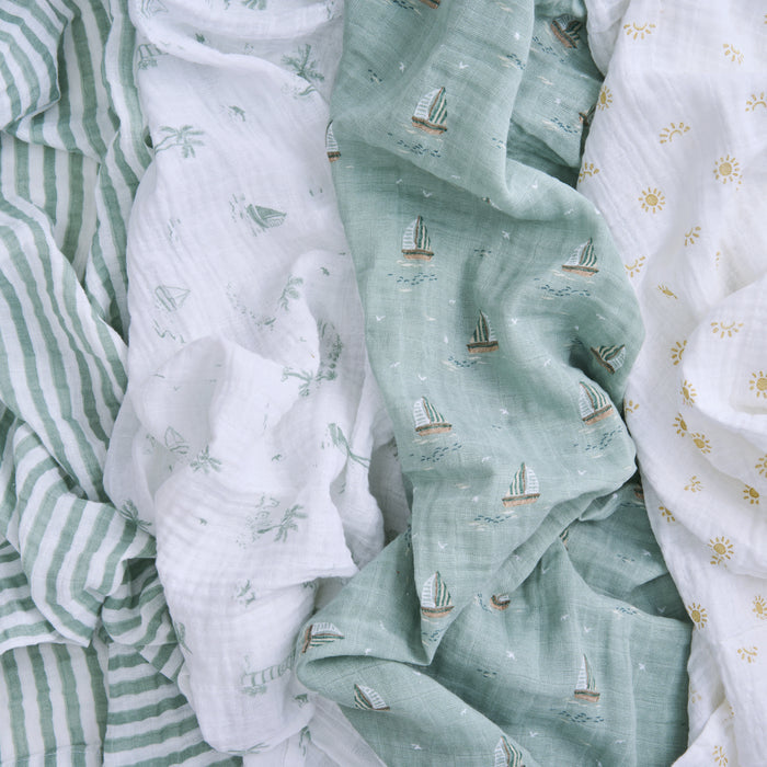 Featuring textured fabrics with green stripes, a white background showcasing green palm trees, and sailboats, the aden + anais organic cotton muslin swaddle blanket 4 pack boasts GOTS certified materials that are layered and slightly rumpled for sustainability and style.