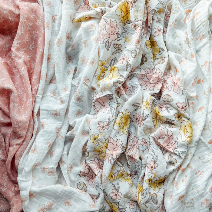 Crafted from 100% organic muslin, the aden + anais swaddle blanket 4 pack features GOTS-certified fabric. Includes pink with white flowers, and white with yellow and pink flowers—designed for gentle comfort for your little one.