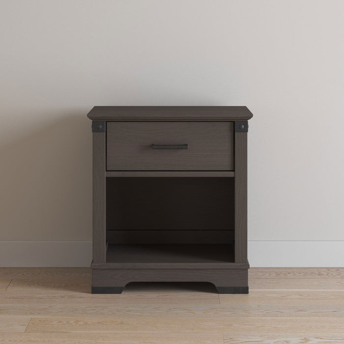 The Child Craft Redmond Nightstand in Dapper Gray features a top drawer and open lower shelf, and is shown against a light wall on a light wood floor.