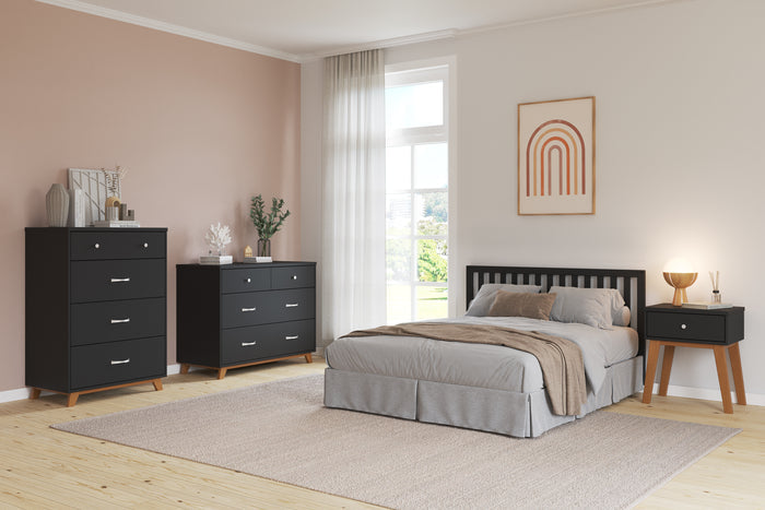 A modern bedroom featuring a black bed frame, gray bedding, the Child Craft Soho Nightstand in Ebony, a matching dresser and chest, light wood flooring, large window with sheer curtains, beige accent wall, and minimalist decor.
