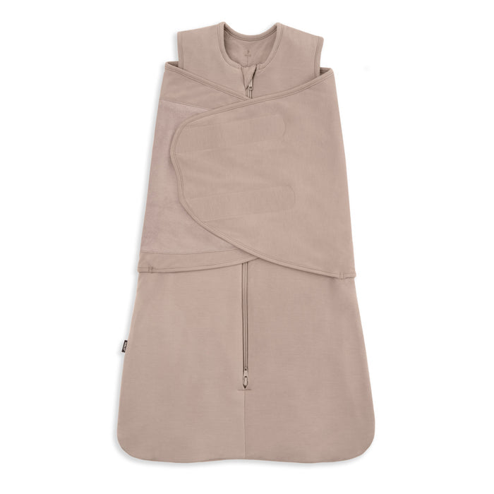 A beige HALO Swaddle SuperSoft Bamboo TOG 2.0, featuring a front zipper, bamboo fabric, and a 3-way adjustable design with velcro straps for wrapping, is laid flat on a white background.