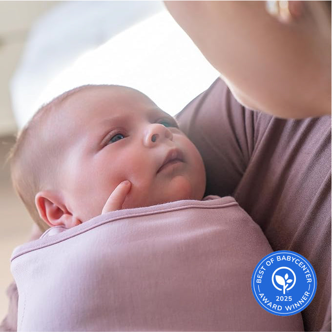 A baby wrapped in a pink swaddle from the HALO Disney Minnie Mouse Bundle gazes up at an adult. A blue Best of BabyCenter Award Winner 2025 badge appears in the lower right corner.