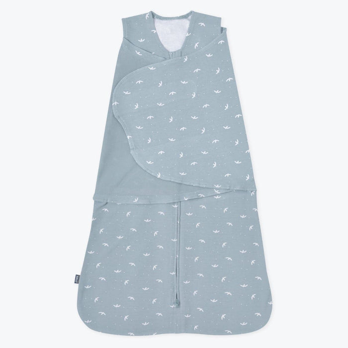 The HALO Swaddle 100% Cotton TOG 1.5 in light blue features a wrap design with white bird patterns, sleeveless with adjustable wings for secure comfort, and a zippered bottom for easy diaper changes while promoting healthy hip development.