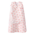 The HALO Swaddle 100% Cotton TOG 1.5 in pink features a floral rose pattern, sleeveless top, and front zipper. Its adjustable wings ensure a snug fit, promoting healthy hip development and comfort for your baby.