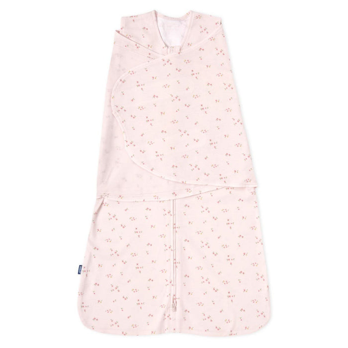 A pale pink HALO Swaddle 100% Cotton TOG 1.5 features a floral design with adjustable wings for healthy hip development and a wrap-around layout.