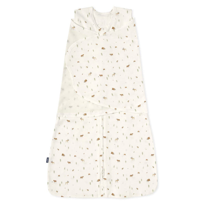 The HALO Swaddle 100% Cotton TOG 1.5 features a cream color with brown and green animal and tree prints. It has a sleeveless design, adjustable wings, and a Velcro-secured wrap-around flap to support healthy hip development for your little one.