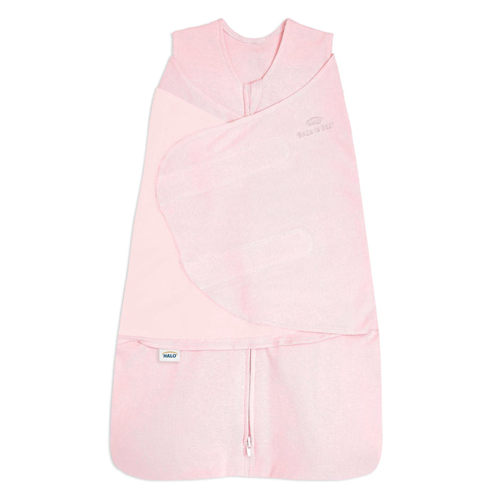 The HALO Swaddle 100% Organic Cotton TOG 1.5 is a light pink, sleeveless swaddle with crossover panels, a bottom zipper, and HALO branding—offering adjustable comfort and convenience for your baby.