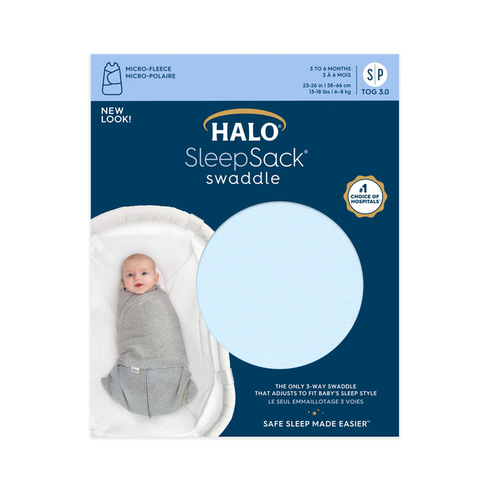 The packaging of a HALO Swaddle Micro-Fleece TOG 3.0 for 3–6 months, size SP, shows a baby in a gray swaddle on a white mattress. It features New Look, Safe Sleep Made Easier, and adjustable wings for healthy hip development with a blue fleece fabric sample.
