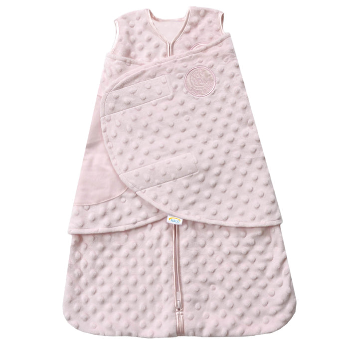 The HALO Swaddle Plushy Dot Velboa TOG 3.0 in light pink has a textured polka dot pattern, front zipper, adjustable wings for secure swaddling with Velcro closure, and an embossed logo on the upper front to promote healthy hip development for your infant.