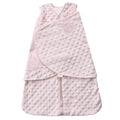 The HALO Swaddle Plushy Dot Velboa TOG 3.0 in light pink has a textured polka dot pattern, front zipper, adjustable wings for secure swaddling with Velcro closure, and an embossed logo on the upper front to promote healthy hip development for your infant.