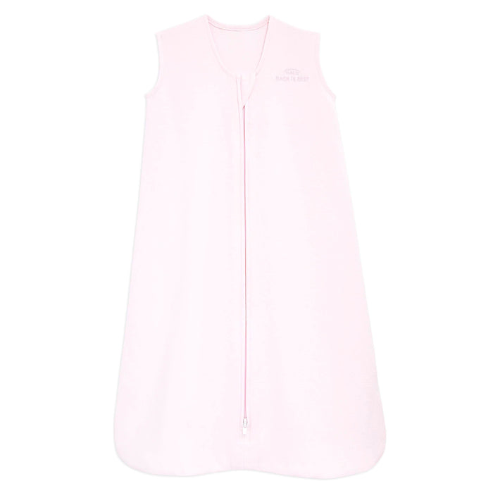 The HALO Wearable Blanket 100% Cotton TOG 0.5 is light pink, sleeveless, with a front zipper and embroidered logo. This blanket ensures safe sleep by keeping babies warm and cozy at night with its soft material.