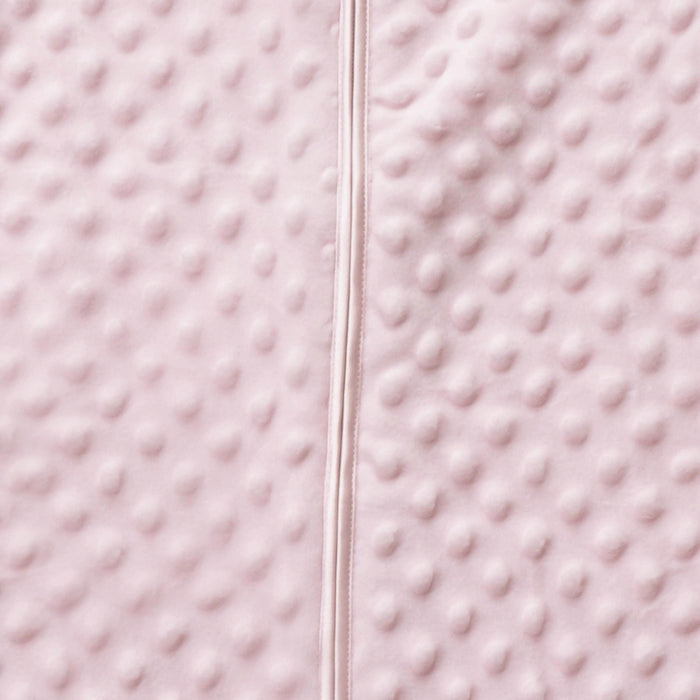 Close-up of HALOs Wearable Blanket Plushy Dot Velboa TOG 1.5 in light pink, showcasing a soft, bumpy texture with a vertical seam. This plush material offers comforting coziness ideal for safe sleep.