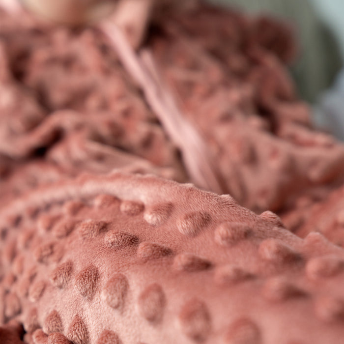 A close-up of the HALO Wearable Blanket Plushy Dot Velboa TOG 1.5 in soft pink, featuring raised dots and cozy texture for a comfortable, safe sleep environment for your baby.
